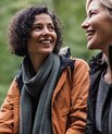 To kvinder sider i skoven og snakker og smiler